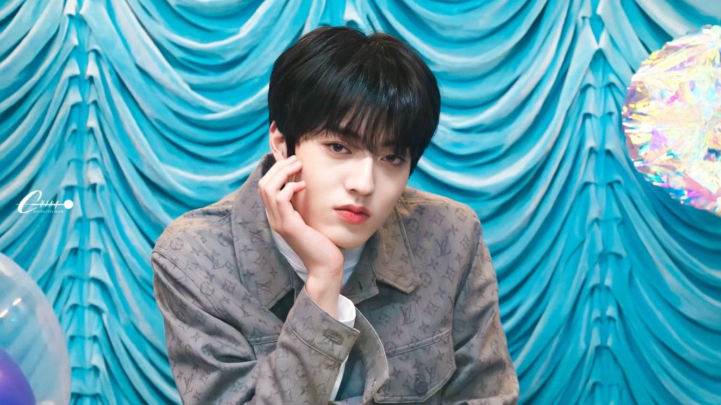 Close-up portrait of K-pop idol Haruto from TREASURE in monogram jacket with blue background Wallpaper