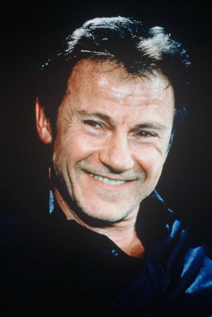 Harvey Keitel portrait with warm smile dramatic lighting black background iconic features wallpaper