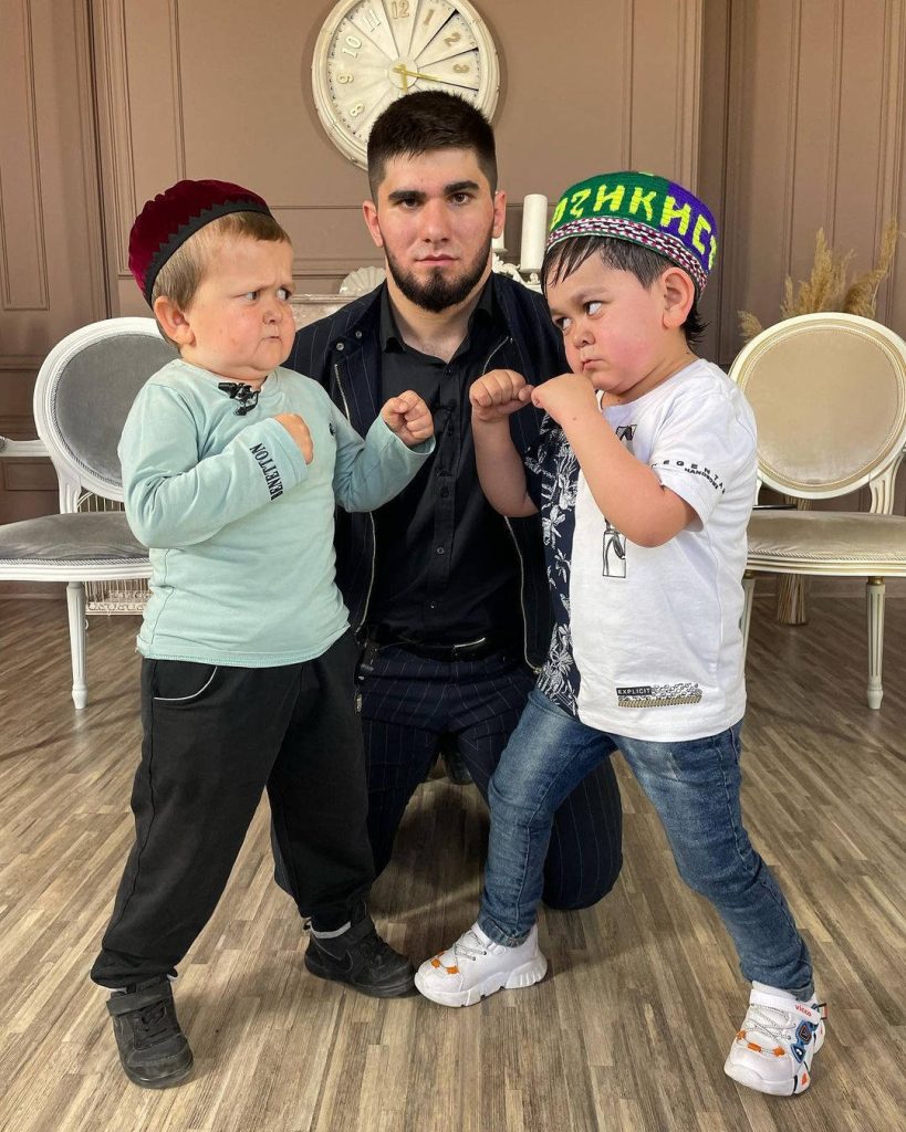 Hasbulla Magomedov boxing pose with sparring partner and referee in elegant classic interior Wallpaper
