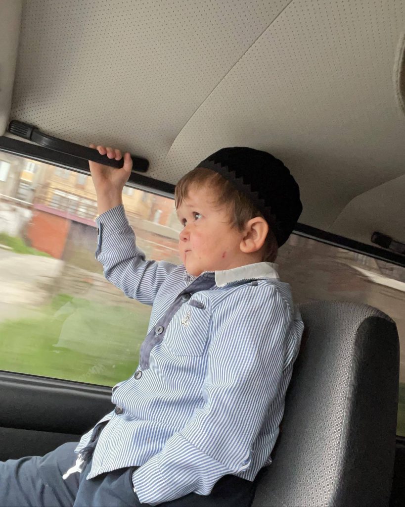 Hasbulla Magomedov in car wearing striped shirt and skullcap holding grab handle looking outside Wallpaper