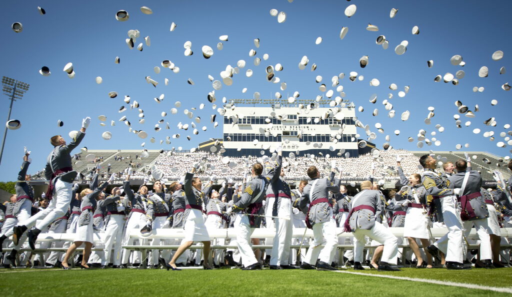 West Point cadets in formal uniforms toss white caps at Michie Stadium celebrating graduation Wallpaper