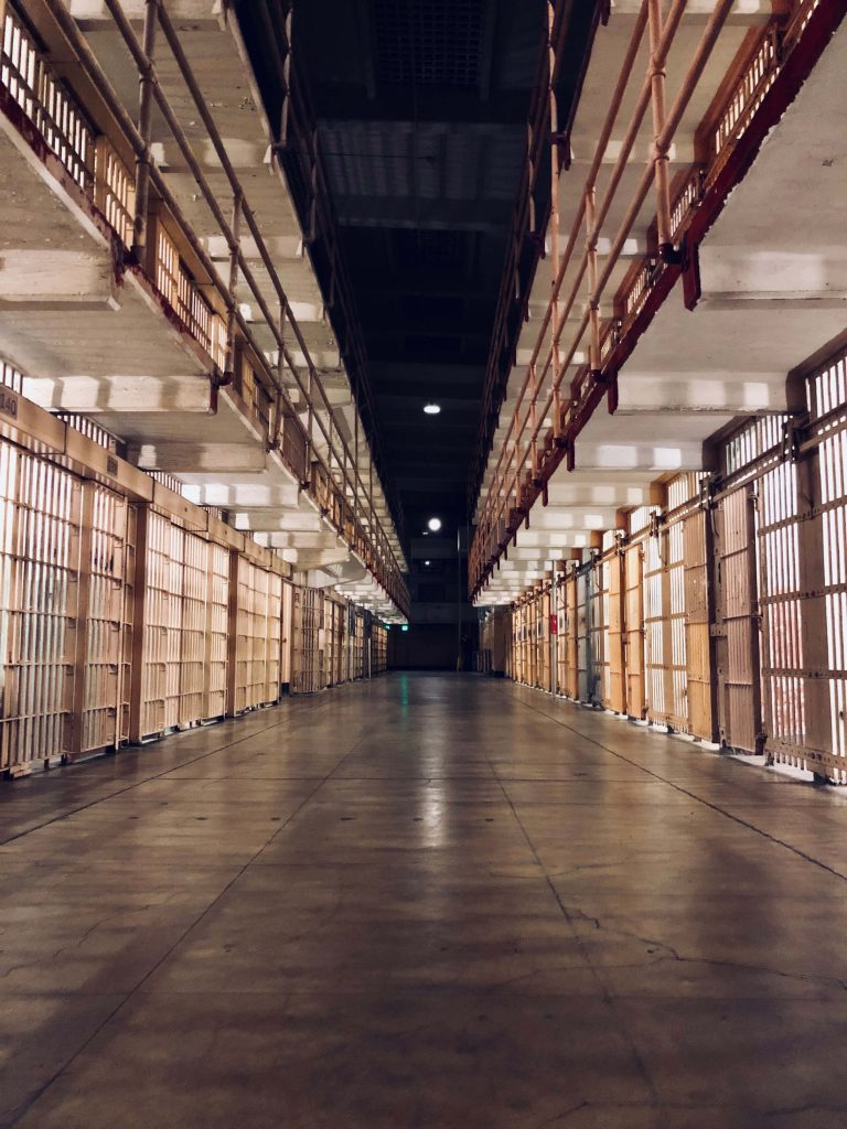 Dimly lit Alcatraz cell block with metal bars and tiered corridors historic prison interior Wallpaper