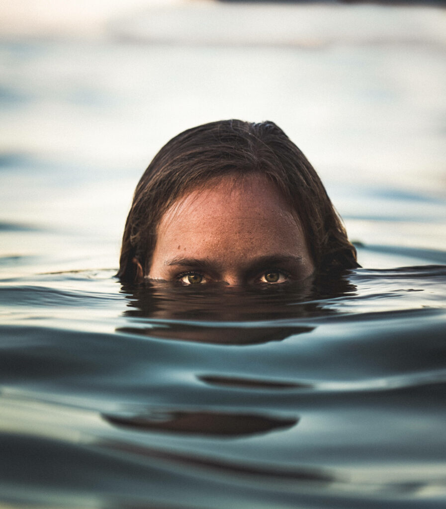 Haunting ghostly face emerging above dark water spooky paranormal wallpaper background