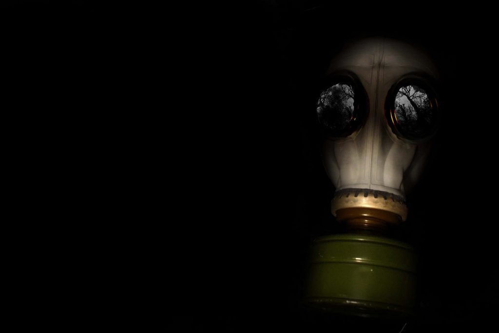 Haunting gas mask in darkness reflecting gloomy forest eerie post-apocalyptic wallpaper background