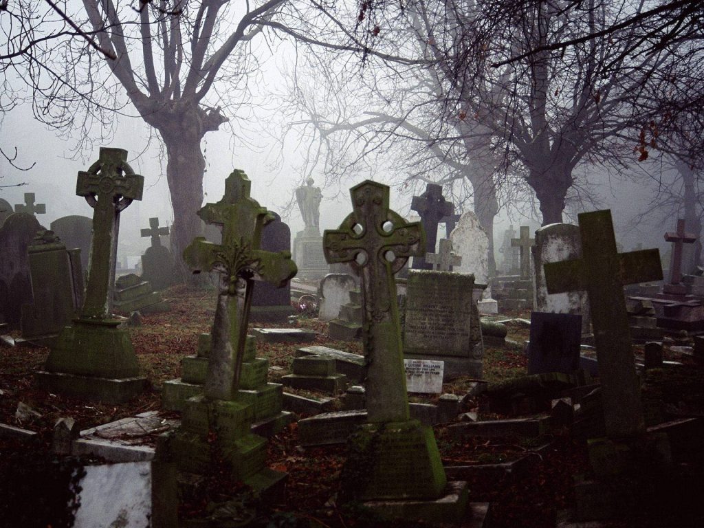 Haunting misty graveyard with weathered Celtic crosses and ancient stone headstones background Wallpaper