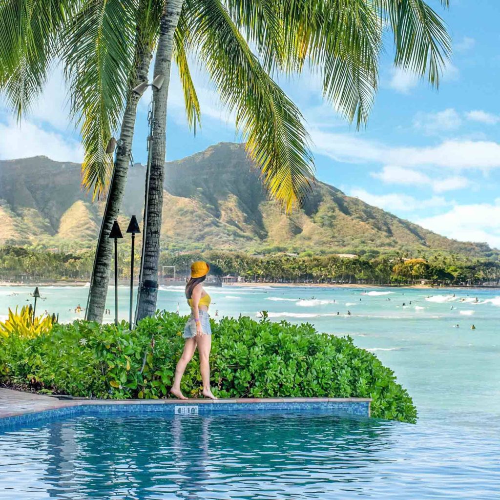 Woman by Oahu infinity pool with Diamond Head crater and turquoise waters tropical wallpaper