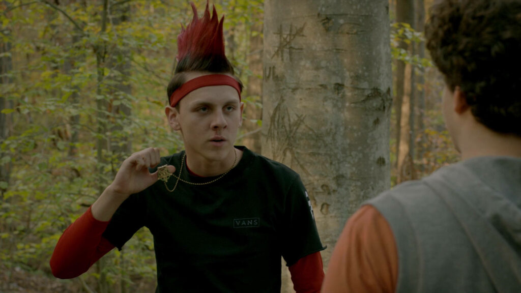 Eli Hawk Moskowitz from Cobra Kai with red mohawk star pendant in forest cinematic wallpaper