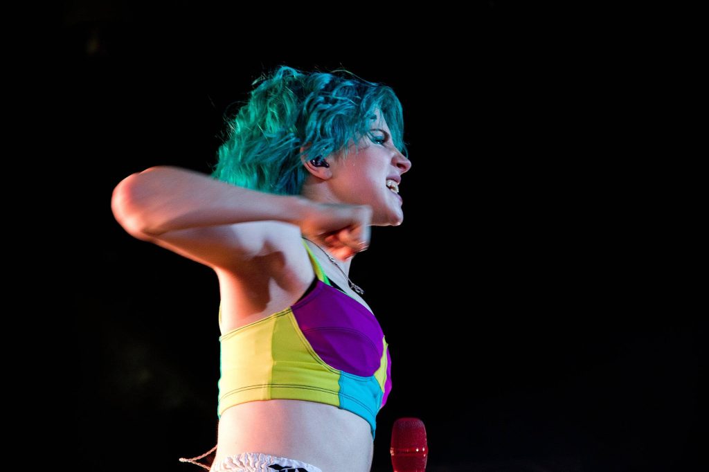 Hayley Williams live concert photo turquoise hair colorful crop top energetic performance background Wallpaper
