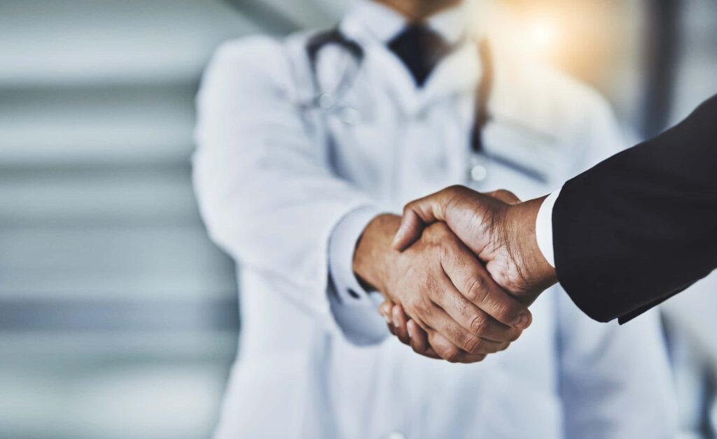Doctor and professional shaking hands symbolizing healthcare partnership and trust teamwork Wallpaper