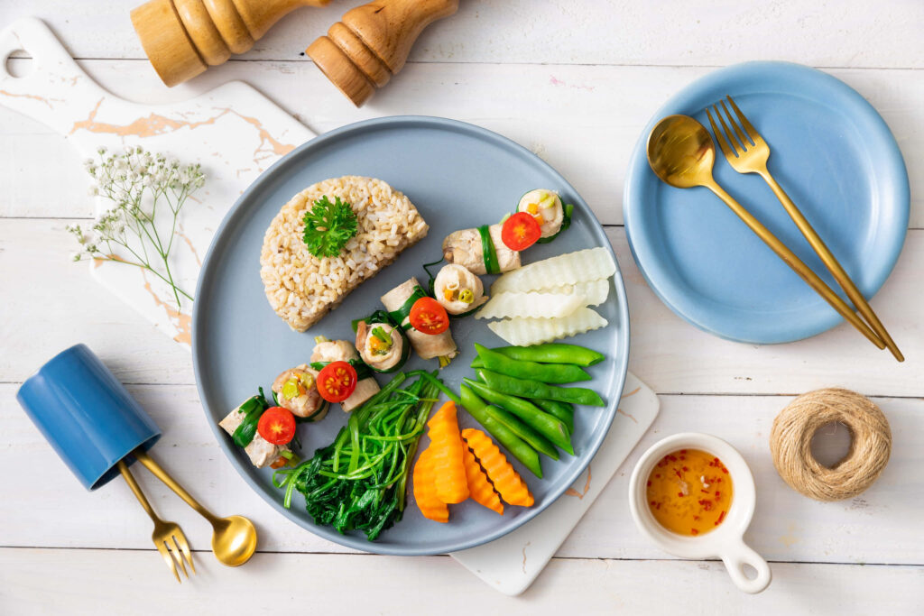 Elegant Healthy Plate: Brown Rice, Veggie Skewers & Golden Cutlery Wallpaper