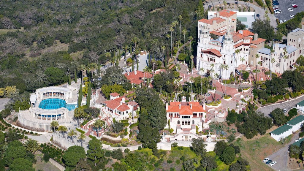 Aerial view of Hearst Castle San Simeon with turquoise Neptune Pool and red-tiled rooftops Wallpaper