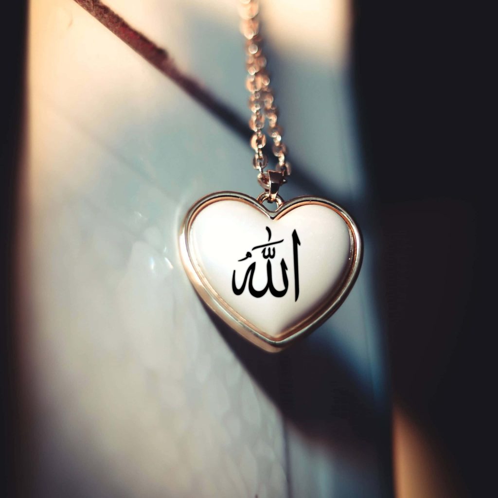 Close-up of heart-shaped pendant with sacred Allah calligraphy on soft dreamy background wallpaper