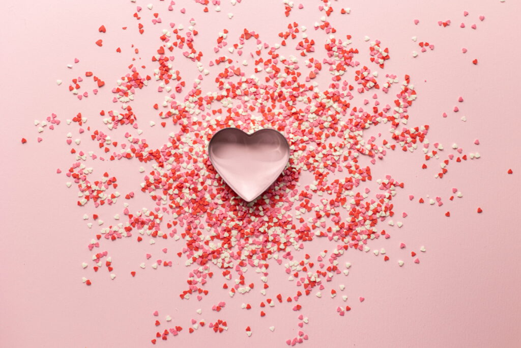 Valentine's Delight: A Lustrous Heart-shaped Baking Tin Sprinkled with Festive Confetti Wallpaper