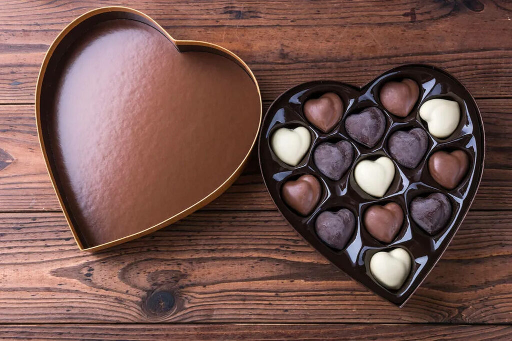 Rustic Heart-Shaped Chocolate Box with Assorted Treats on Wood Wallpaper