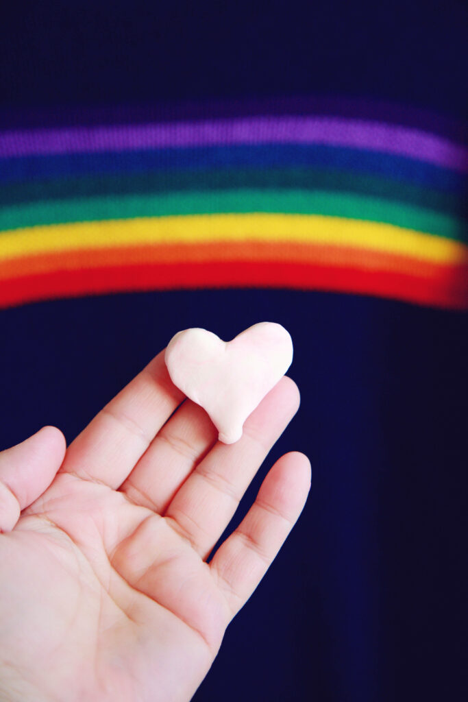 Colorful Rainbow Heart Wallpaper: Whimsical Hand-Held Design