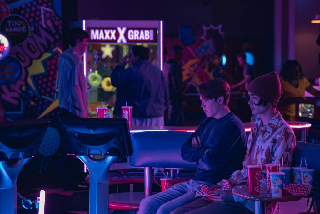 Heartstopper arcade wallpaper with Charlie Spring Tao Xu neon blue purple lighting background