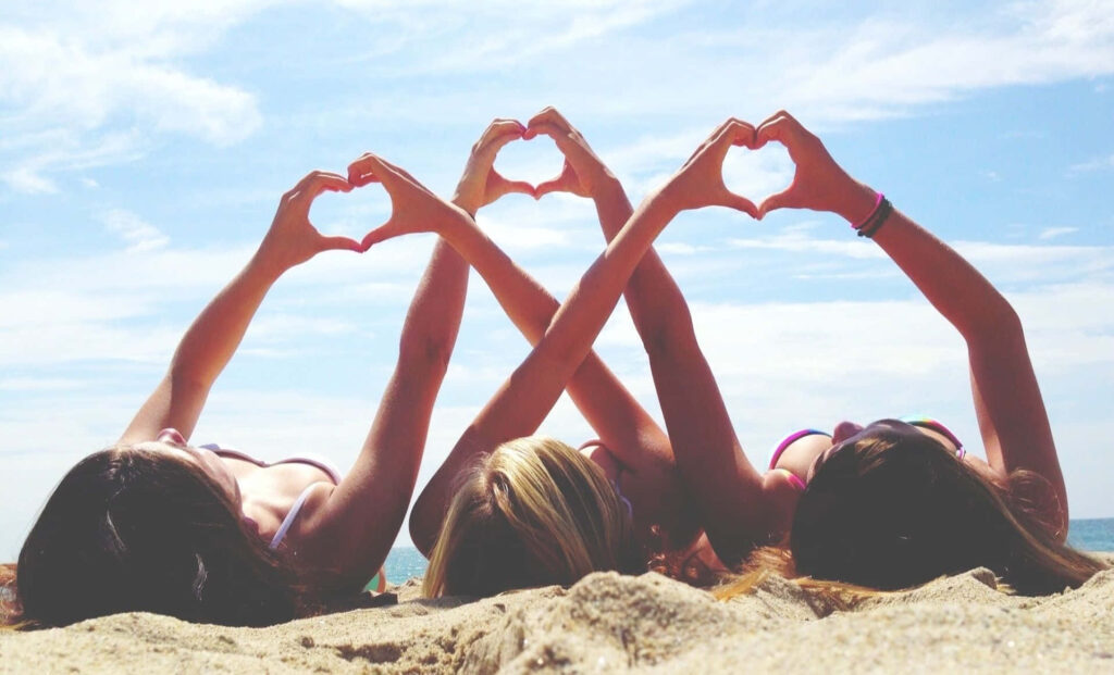 Heartwarming Beach Wallpaper: Friends Celebrating Moments in Heart Shapes