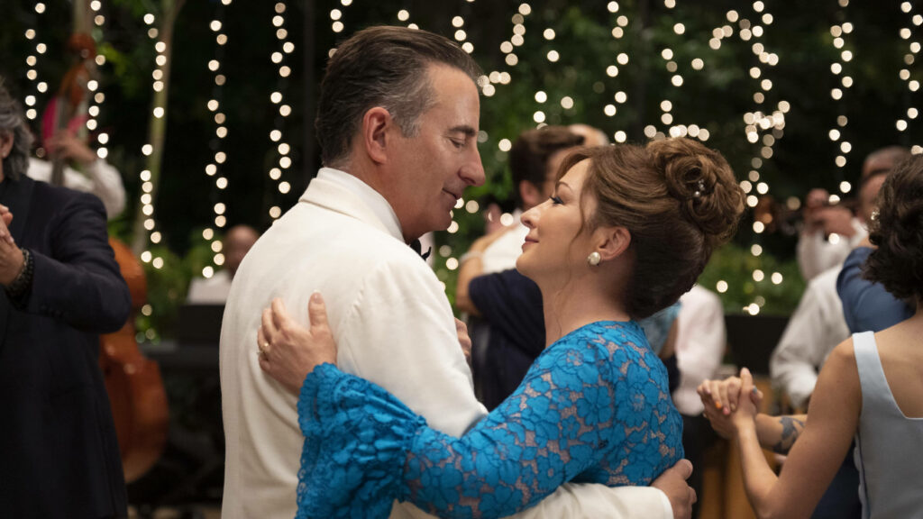 Father and daughter dancing at wedding with glowing string lights and joyful guests background Wallpaper