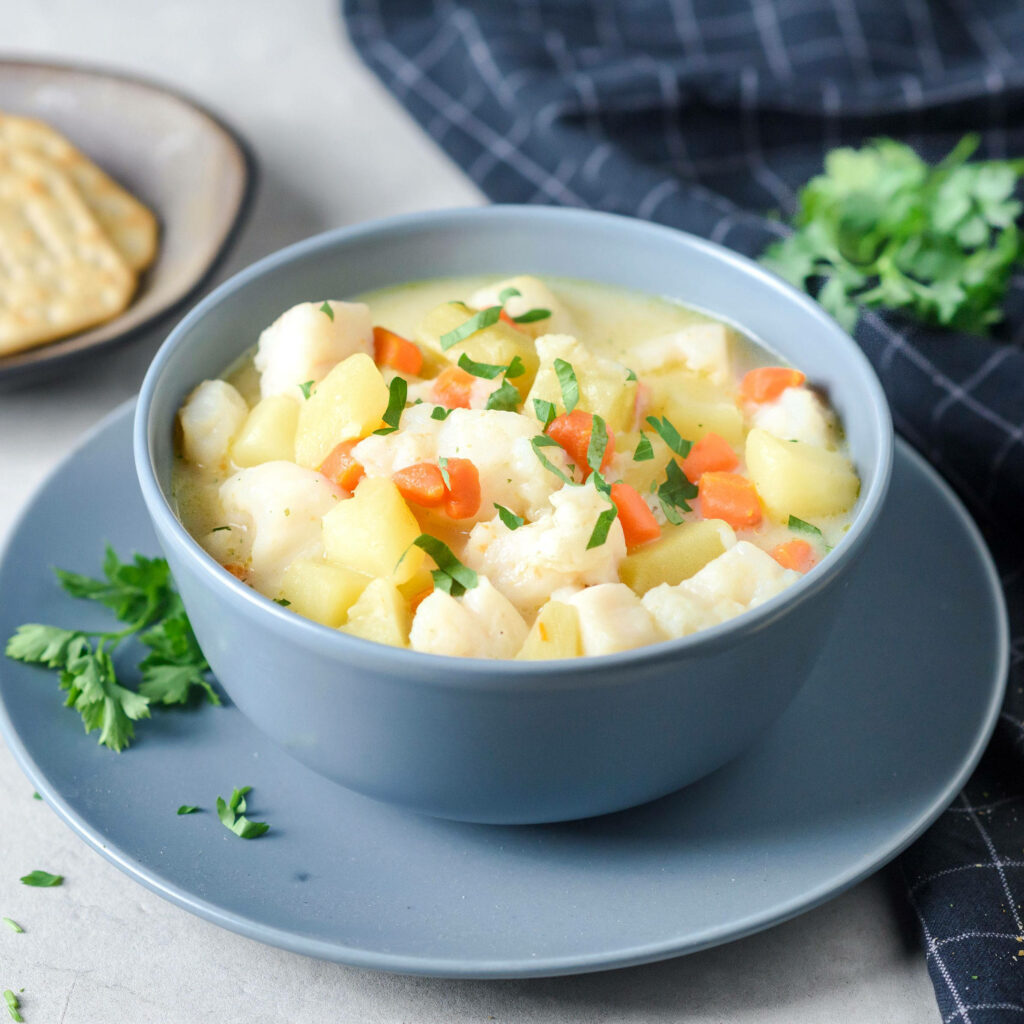 Hearty fish potato chowder with creamy broth carrots and parsley in vibrant wallpaper background