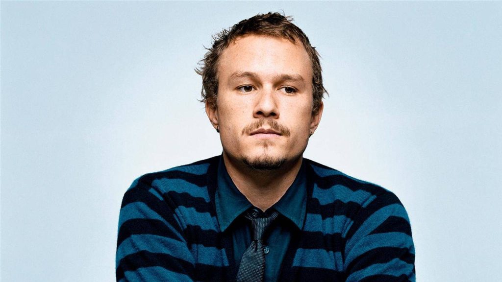 Heath Ledger studio portrait wearing striped cardigan and collared shirt on light blue background Wallpaper