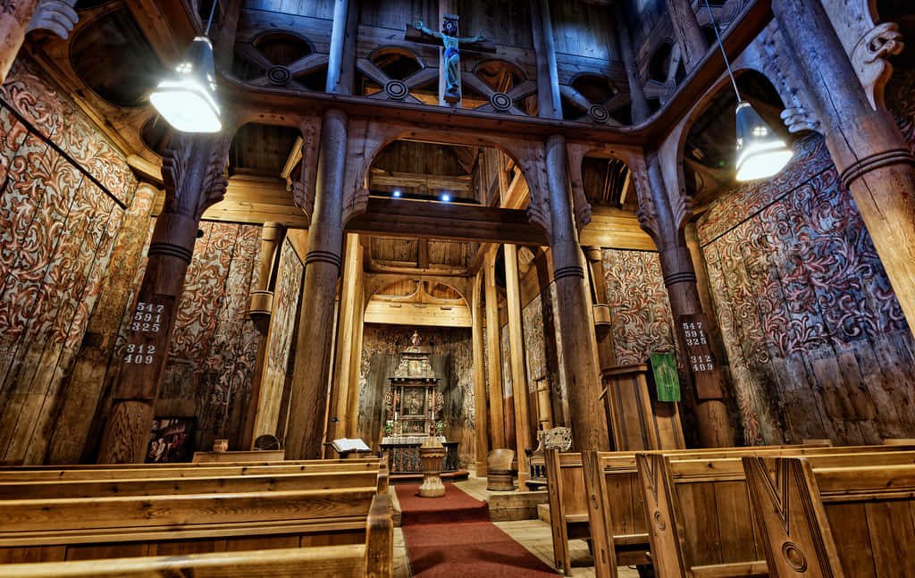 Interior of Norway Heddal Stave Church with wooden columns medieval paintings warm lighting wallpaper