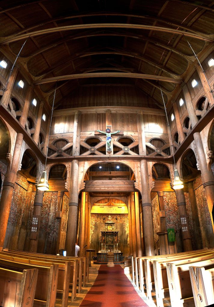Interior view of Norway’s Heddal Stave Church timber architecture with crucifix and beams wallpaper