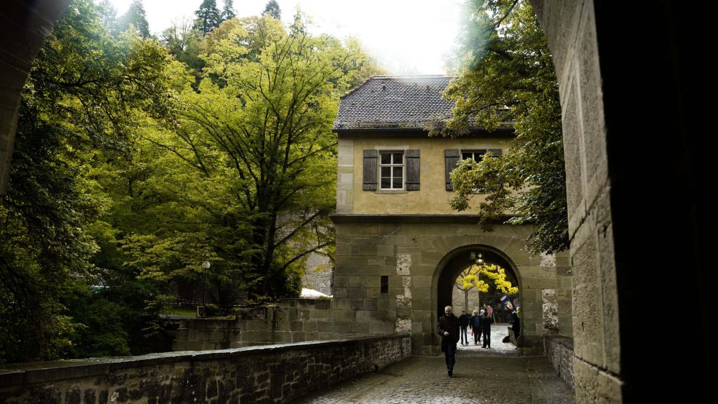 Heidelberg Castle arched stone gateway with cobblestone path and green foliage travel wallpaper