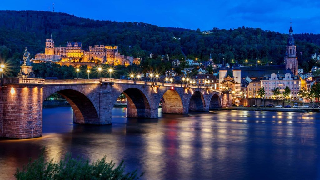 Heidelberg Castle and Old Bridge glowing at twilight reflecting on Neckar River calm waters Wallpaper