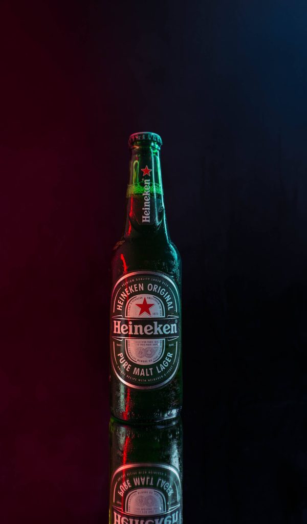 Condensation covered Heineken beer bottle on dark surface with red and blue rim lighting Wallpaper