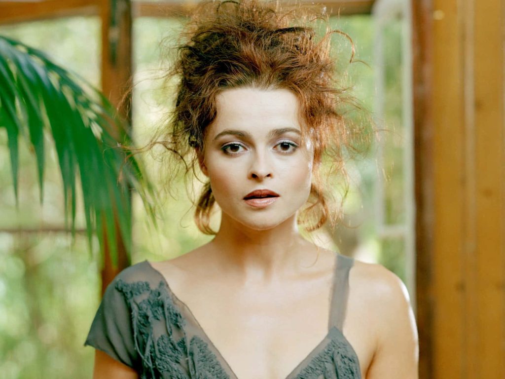 Portrait of Helena Bonham Carter with messy auburn updo in vintage grey dress and greenery background Wallpaper