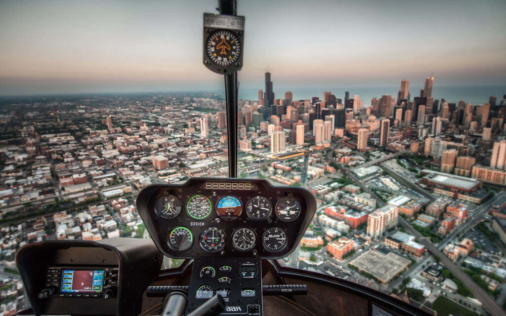 Helicopter cockpit view over city skyline at sunset with detailed flight instruments and skyscrapers Wallpaper