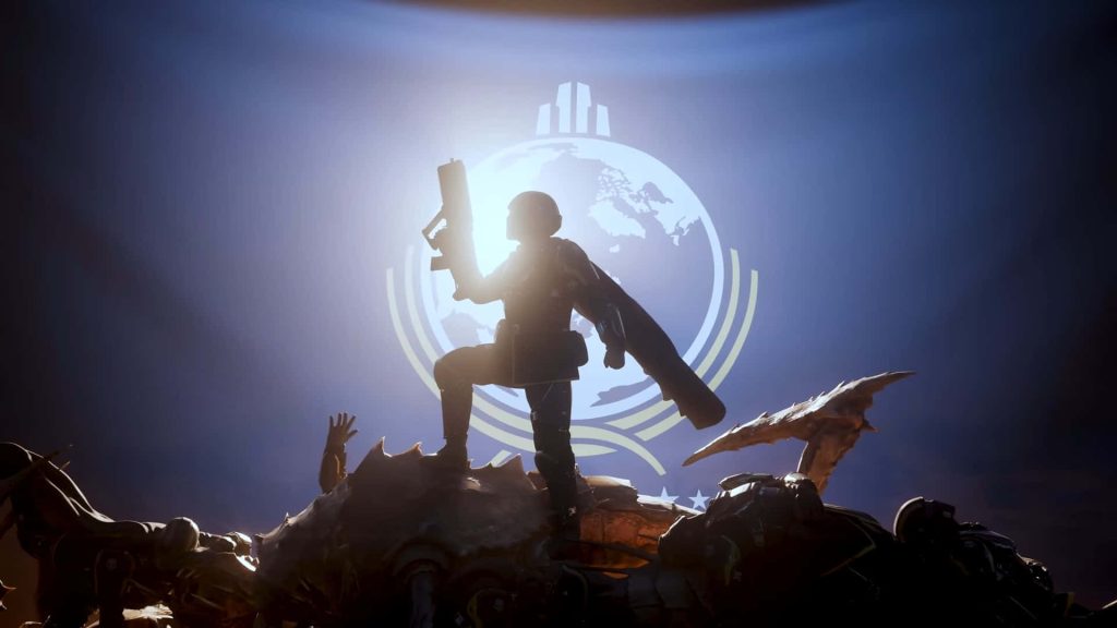 Heroic soldier victory pose on defeated Terminid with glowing Super Earth emblem in Helldivers 2 Wallpaper