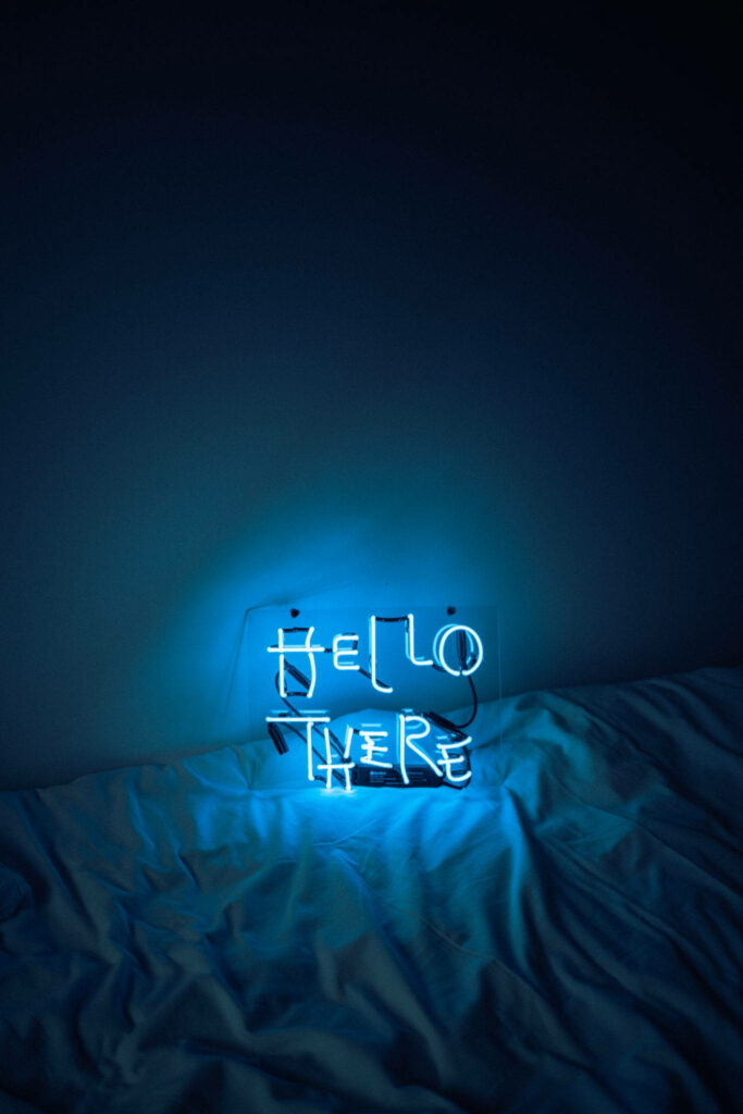 Hello There: Aesthetic Blue LED Sign Illuminates a Messy Bed Sheet Wallpaper