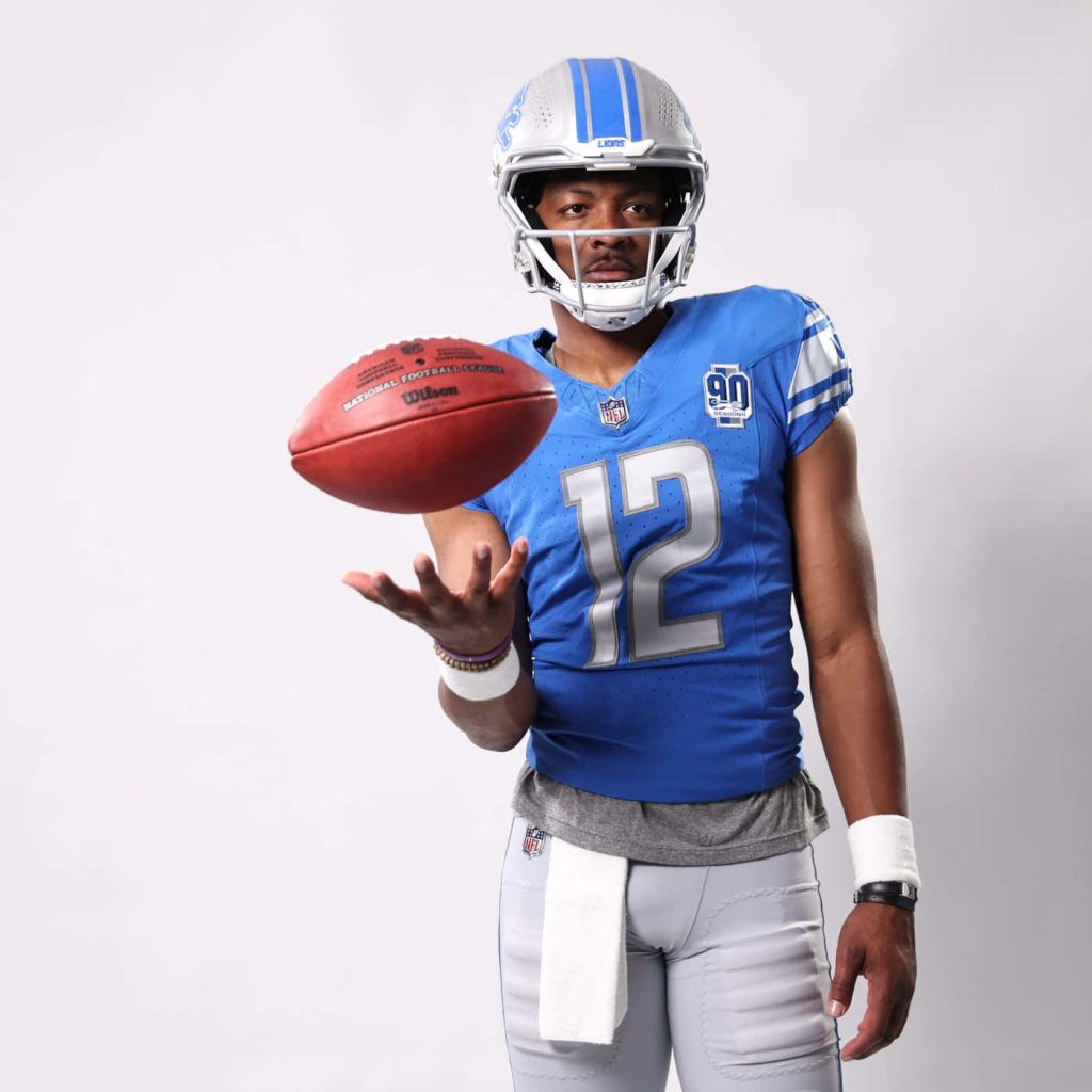 Hendon Hooker Detroit Lions quarterback in blue silver uniform holding football studio portrait Wallpaper