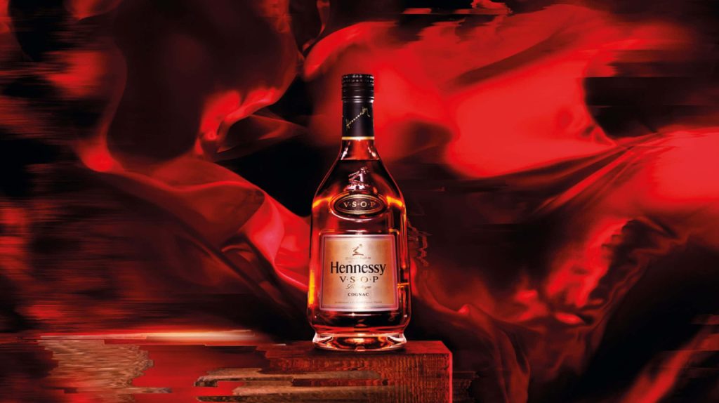 Elegant Hennessy VSOP Privilège Cognac bottle with glitch-style red light on wooden block background Wallpaper
