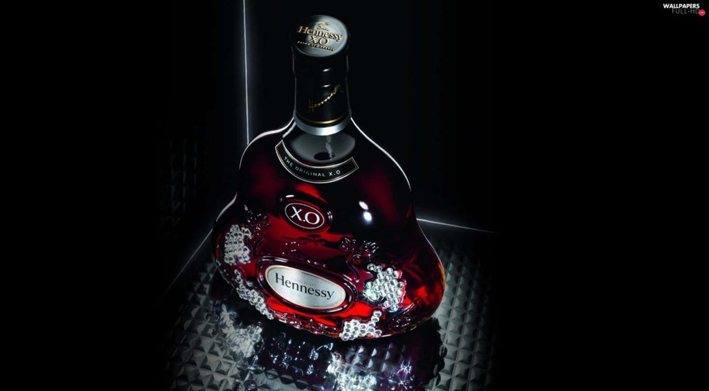Hennessy XO Cognac bottle on reflective surface with black background premium wallpaper