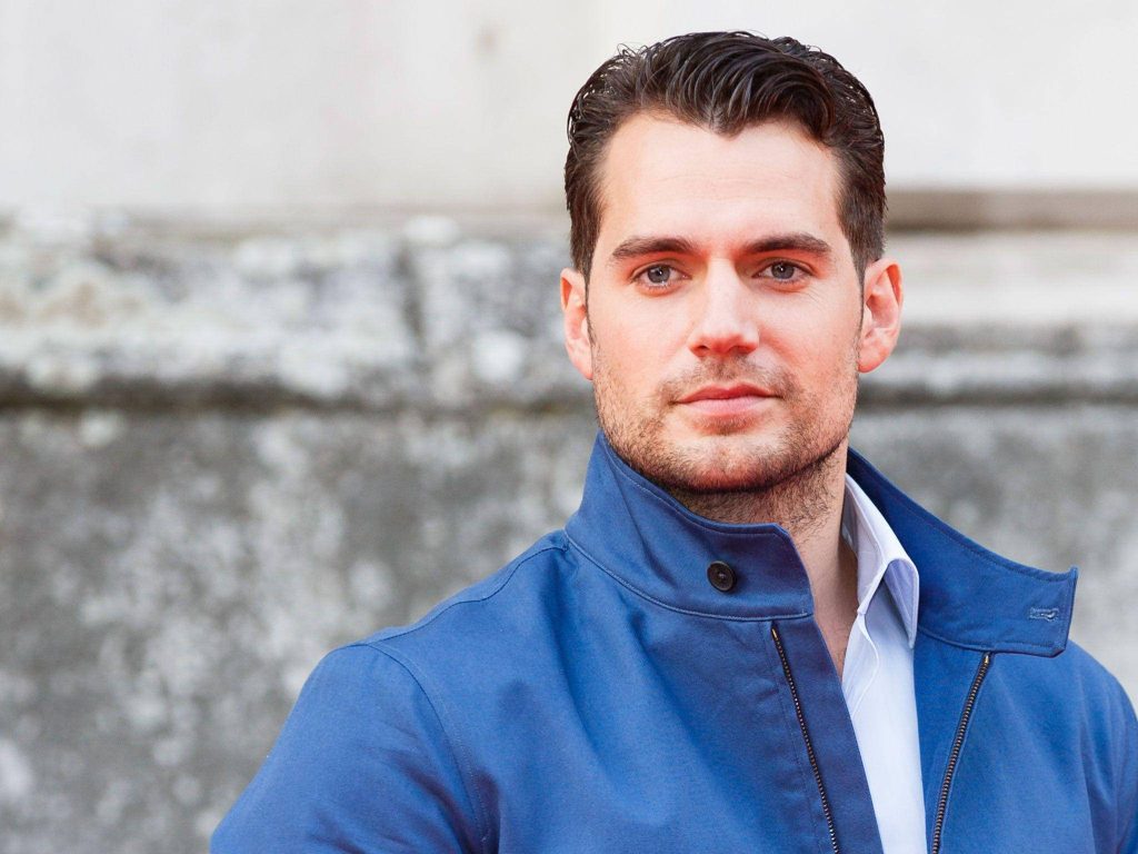 Henry Cavill portrait in blue jacket with bright natural light and soft-focus stone background Wallpaper