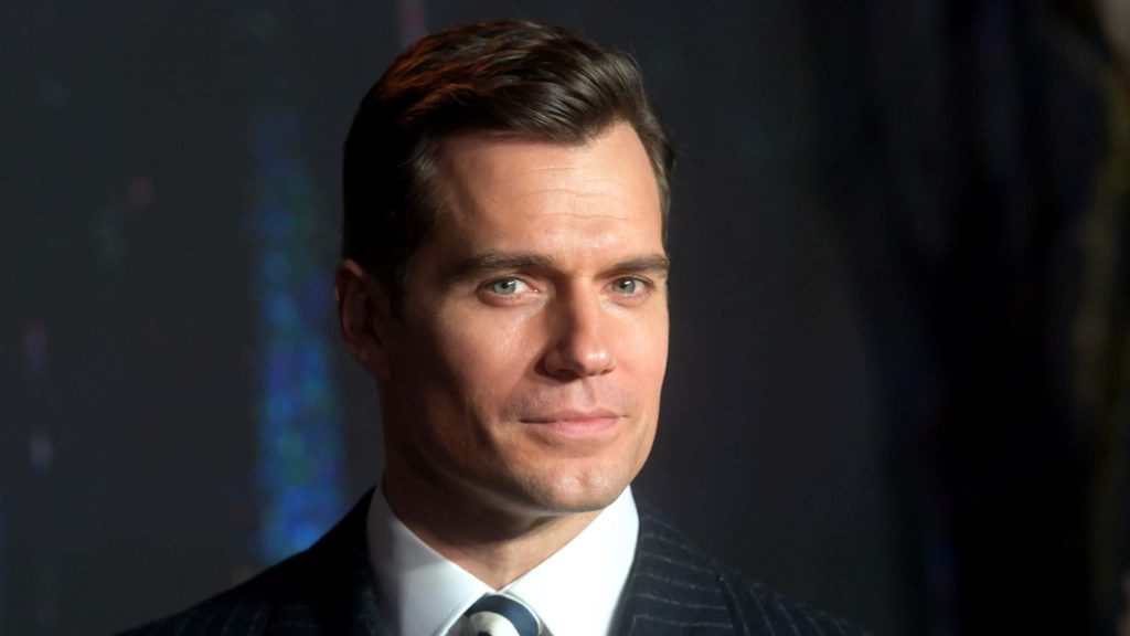 Henry Cavill portrait in sharp suit with confident smirk soft studio lighting dark background wallpaper