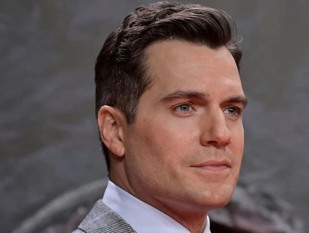 Henry Cavill portrait in grey suit with subtle smile on neutral background high-resolution wallpaper