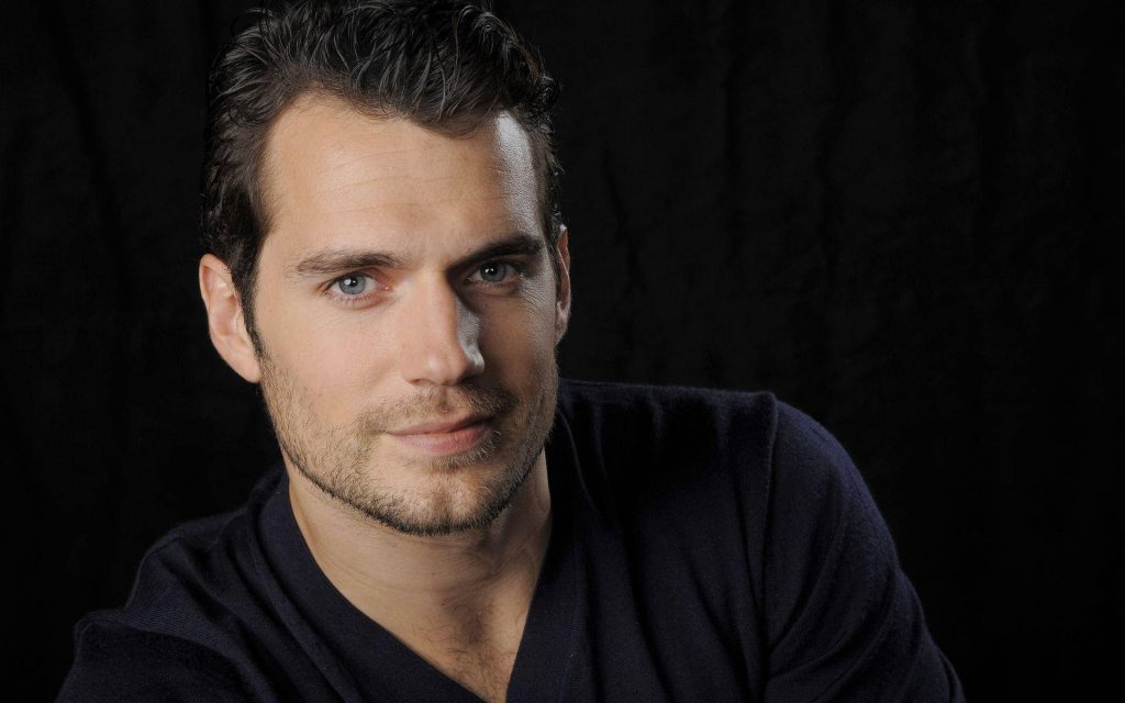 Henry Cavill portrait with piercing blue eyes dark hair subtle stubble moody black background wallpaper