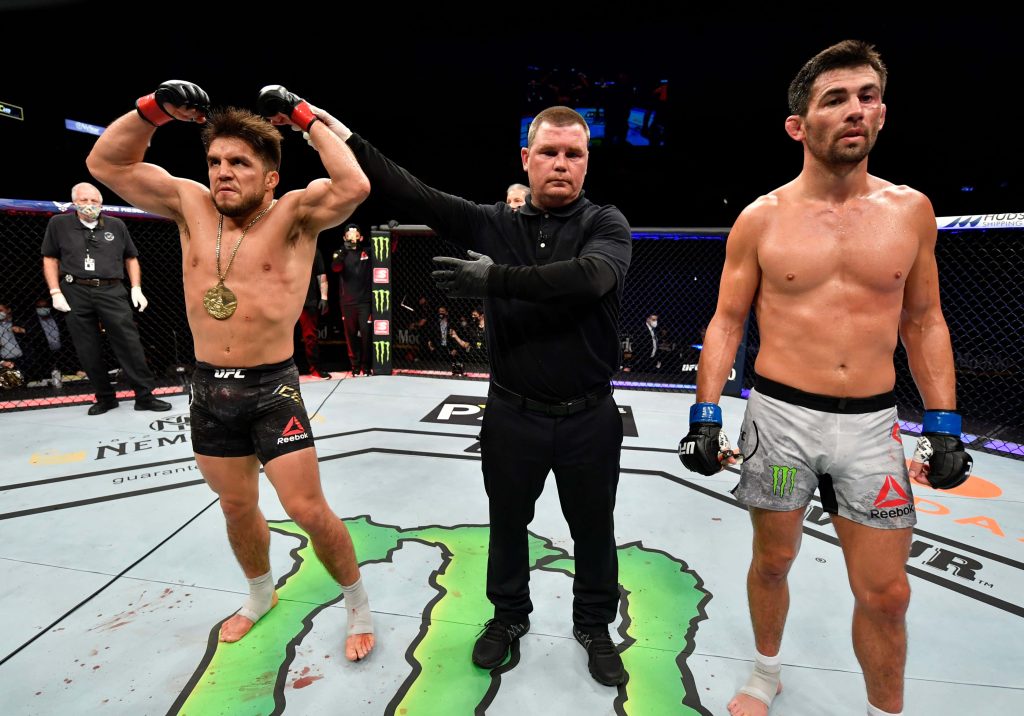Henry Cejudo celebrates UFC 249 win with referee Keith Peterson on Monster Energy octagon background Wallpaper