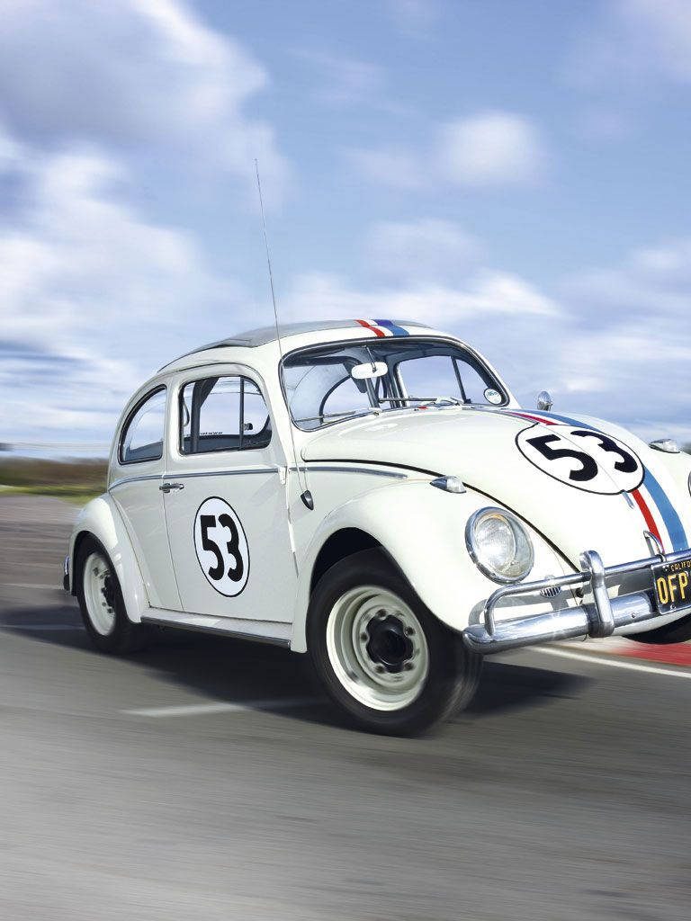 Herbie the white Volkswagen Beetle number 53 racing fast with motion blur on track wallpaper