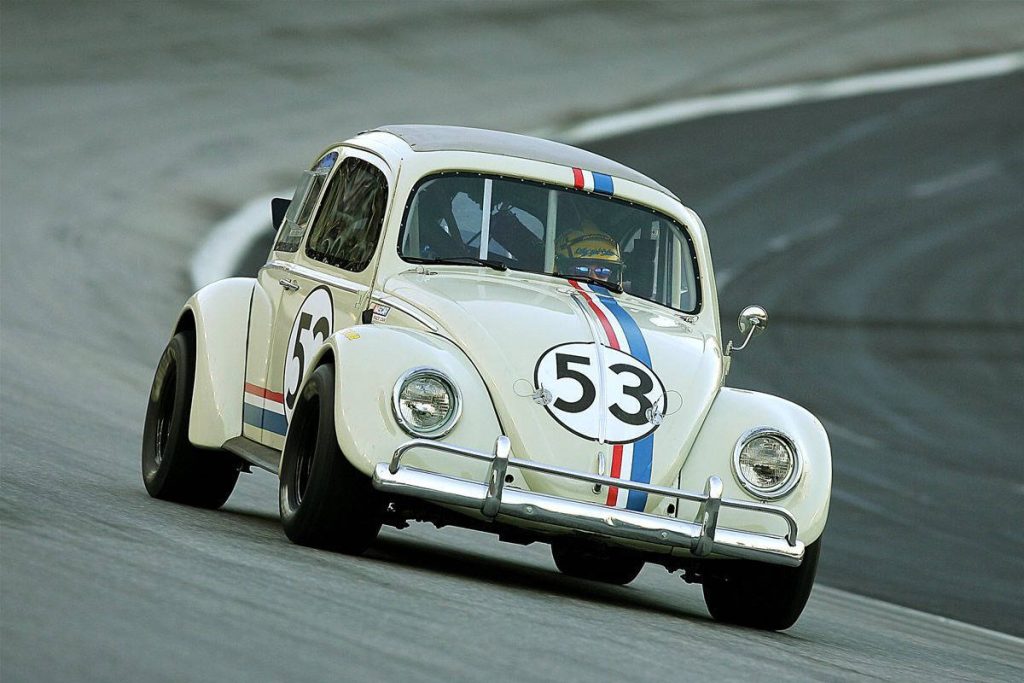 Herbie Fully Loaded white VW Beetle with red white blue stripes racing on NASCAR track wallpaper