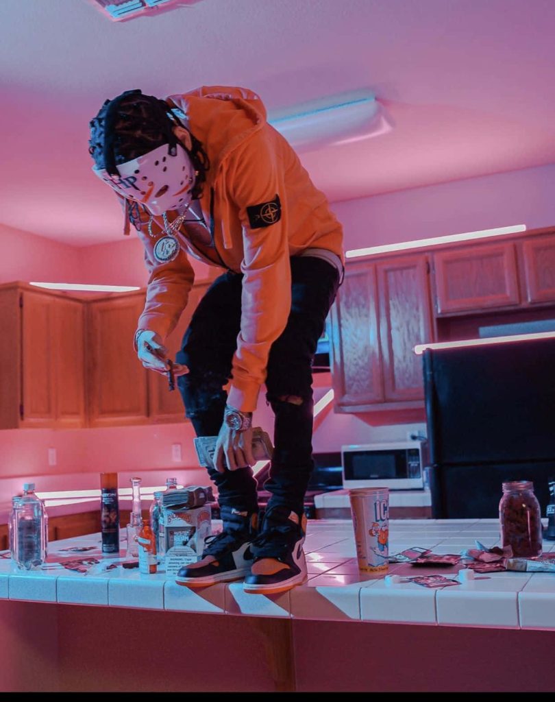 Herencia de Patrones trap wallpaper with neon lights figure in Jason mask orange Stone Island hoodie