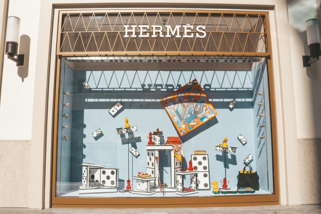 Hermes window display with oversized dominoes luxury bags colorful scarf stylish backdrop wallpaper