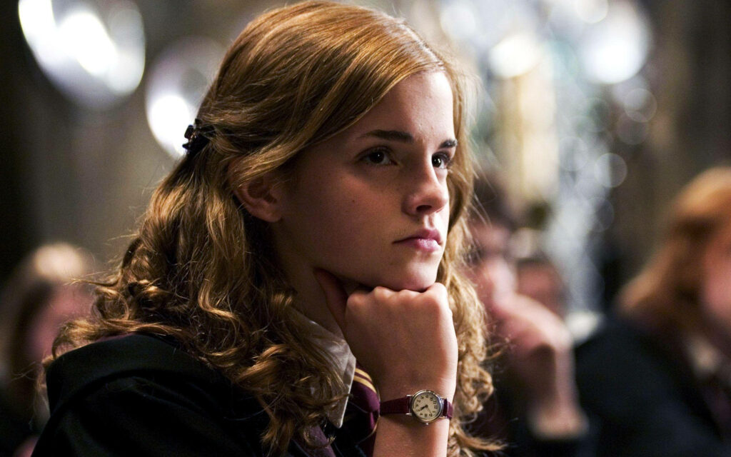 Close-up of Hermione Granger in Hogwarts uniform with wavy hair thoughtful pose wallpaper