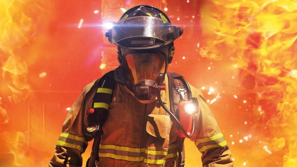 Heroic firefighter close-up in full gear and SCBA mask surrounded by intense flames wallpaper