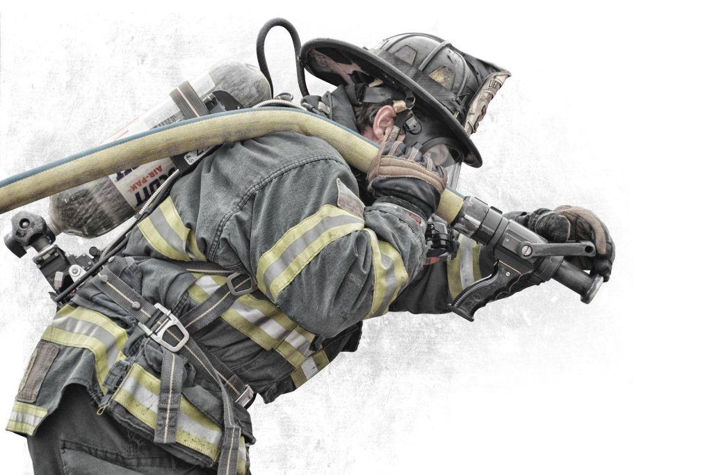 Firefighter lieutenant in full gear using water hose nozzle honoring first responders wallpaper