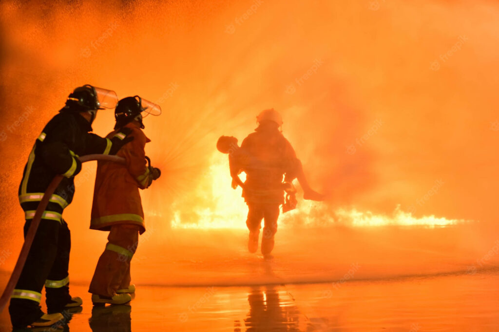Brave fireman rescues victim from blazing fire heroic firefighters control flames wallpaper