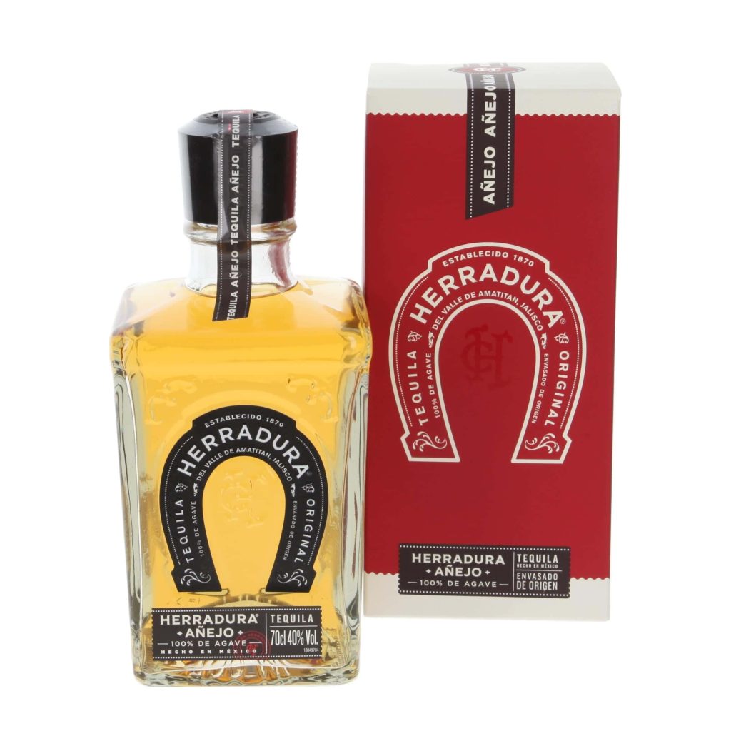 Herradura Añejo Tequila bottle with amber liquid beside red white box on white background Wallpaper